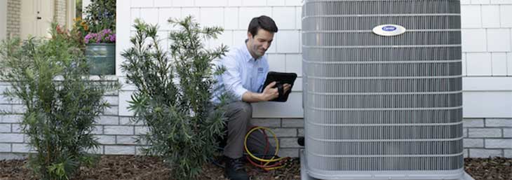 Carrier technician inspecting an energy-efficient residential heat pump.